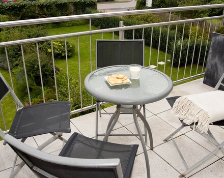 Balkon mit Gartenmöbeln und Blick auf die Dünen