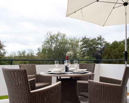 Großer Balkon mit Blick über Gärten auf die Dünen
